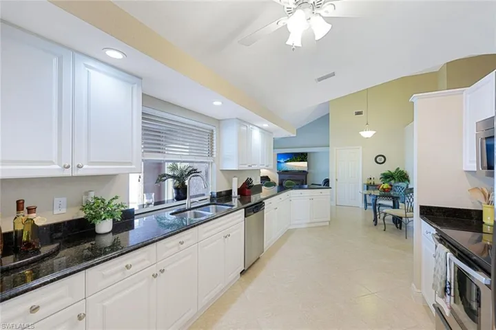 Kitchen with white cabinetry, sink, dark stone countertops, pendant lighting, and appliances with stainless steel finishes
