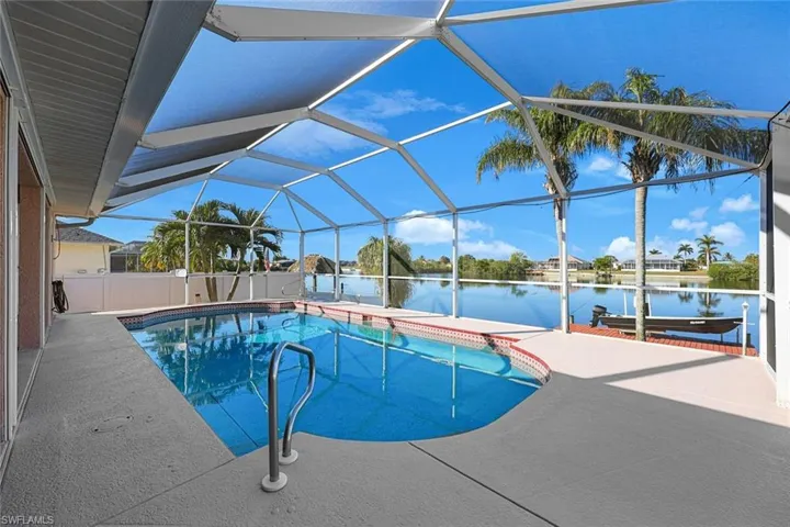 View of swimming pool with a boat dock, a patio, a water view, and glass enclosure
