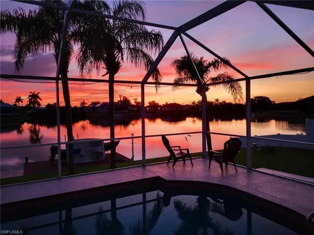 Pool at dusk featuring a water view and a lanai