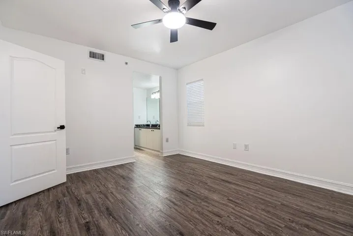 Unfurnished room with dark wood-style flooring and ceiling fan