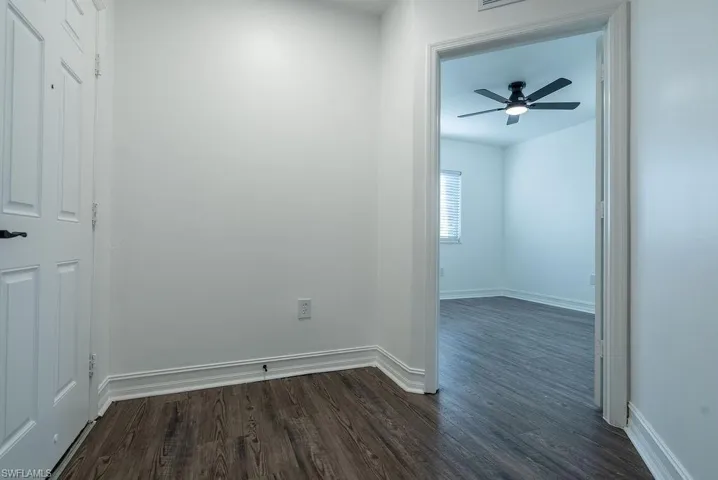 Empty room with dark wood-style flooring and ceiling fan