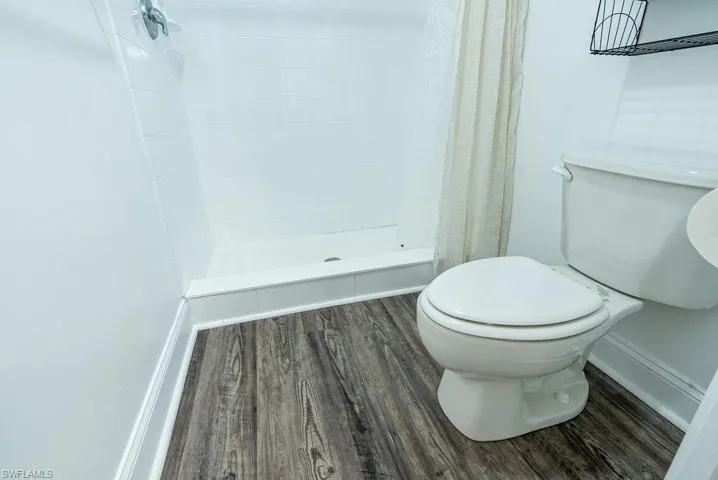 Full bathroom featuring wood finished floors and a stall shower