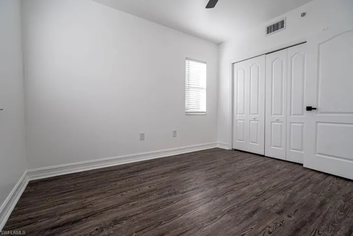 Unfurnished bedroom featuring dark wood-style floors, a closet, and a ceiling fan