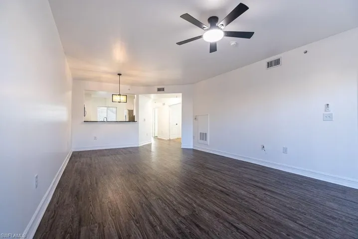 Unfurnished living room with dark wood-style floors and a ceiling fan