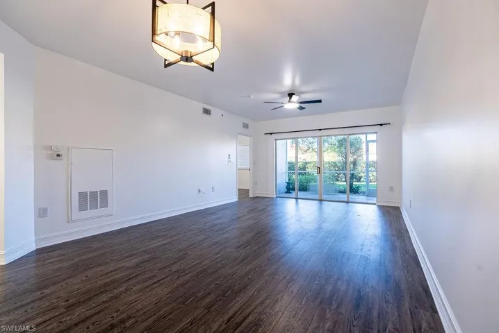 Unfurnished living room with dark wood-style floors and a ceiling fan
