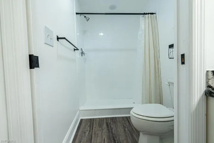 Bathroom featuring dark wood-type flooring and a stall shower