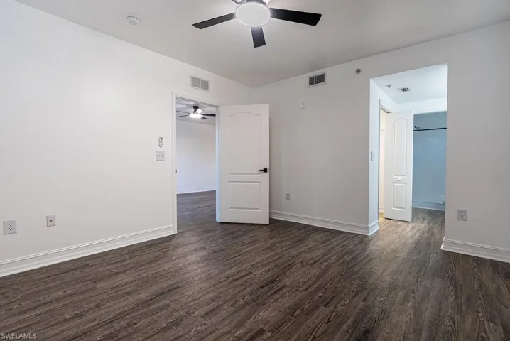 Unfurnished room featuring dark wood-style floors and ceiling fan