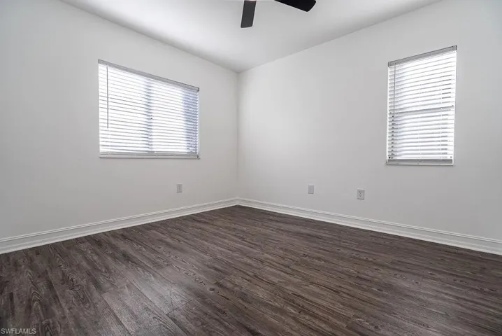 Spare room with dark wood-style floors and a ceiling fan