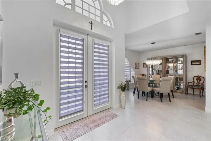 Entryway featuring french doors, a chandelier, and light tile patterned floors