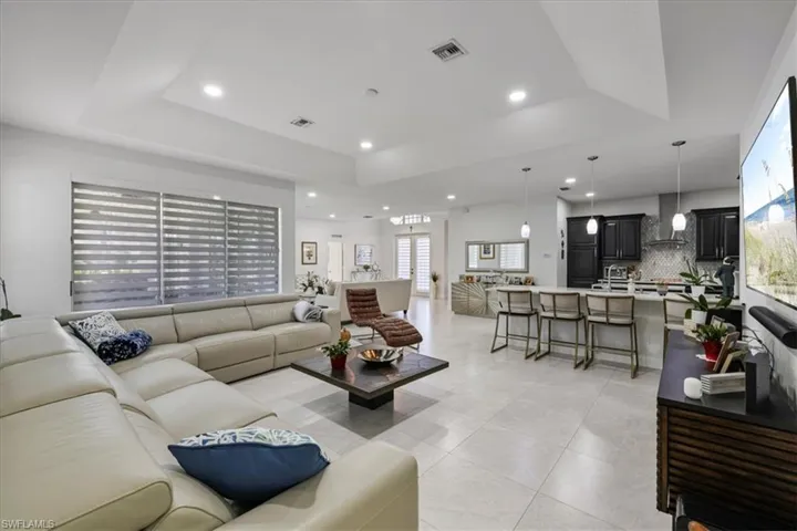 Living area featuring light tile patterned floors, recessed lighting, and a raised ceiling