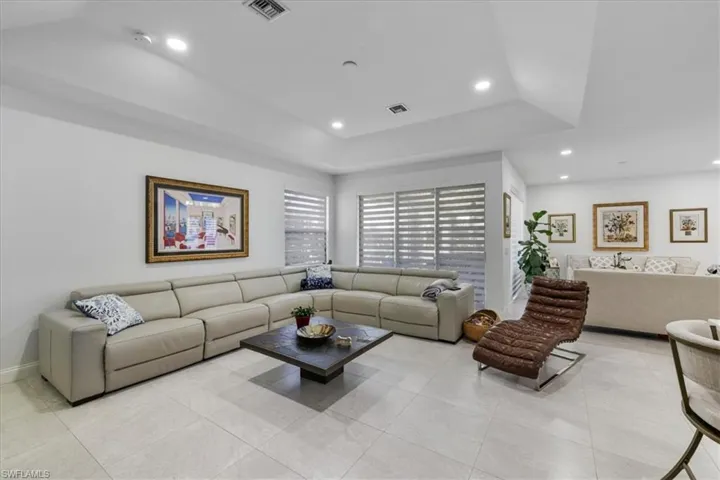 Living area with light tile patterned flooring, recessed lighting, and a tray ceiling