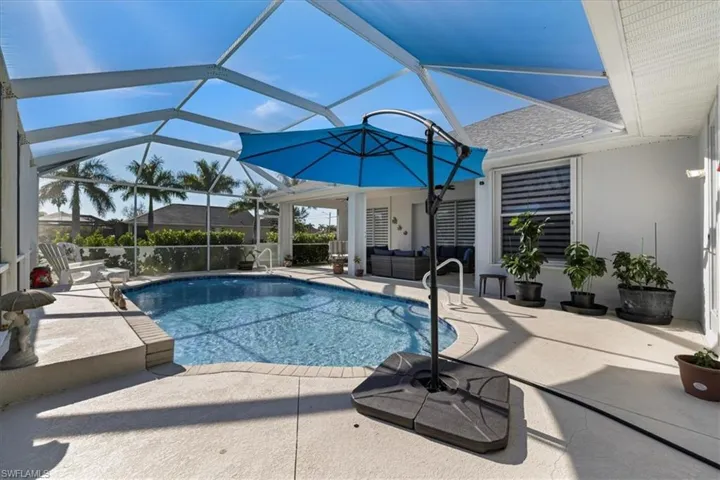 Swimming pool featuring a patio area, glass enclosure, a sunroom, and an outdoor living space