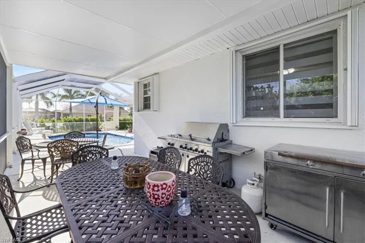 View of patio with outdoor dining area, a sunroom, an outdoor pool, and area for grilling