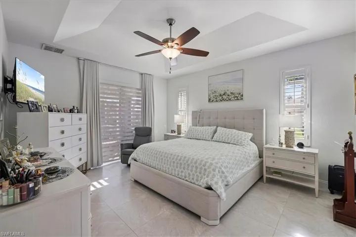 Bedroom with a tray ceiling, multiple windows, and ceiling fan