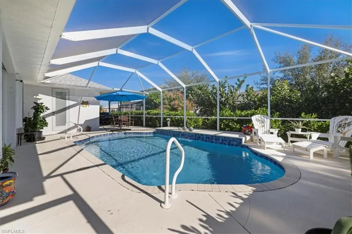 Swimming pool featuring a sunroom, glass enclosure, and a patio area