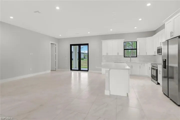 Kitchen with backsplash, stainless steel appliances, sink, a center island, and white cabinetry