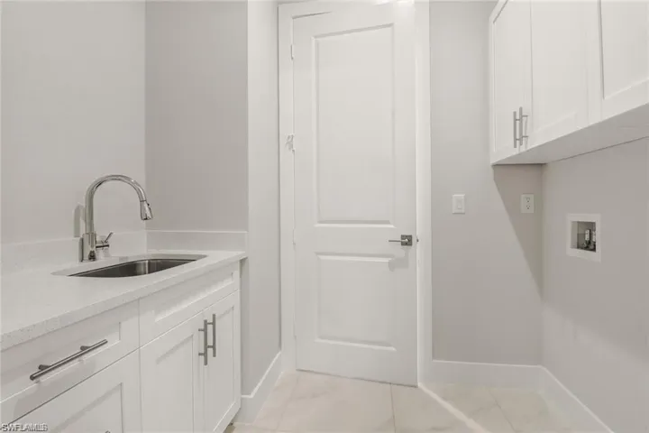 Laundry room featuring cabinets, hookup for a washing machine, light tile patterned floors, and sink
