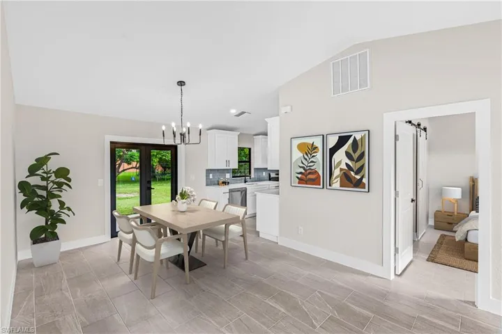 Virtually Staged -Dining area featuring lofted ceiling, french doors, a chandelier, and a barn door