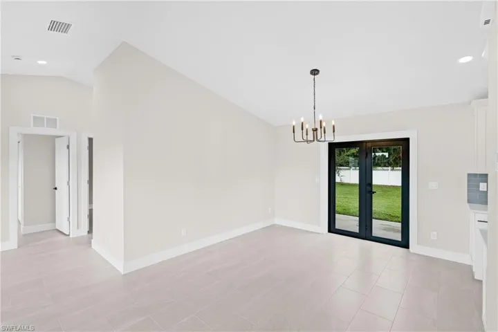 Unfurnished dining area with recessed lighting, lofted ceiling, a chandelier, and french doors