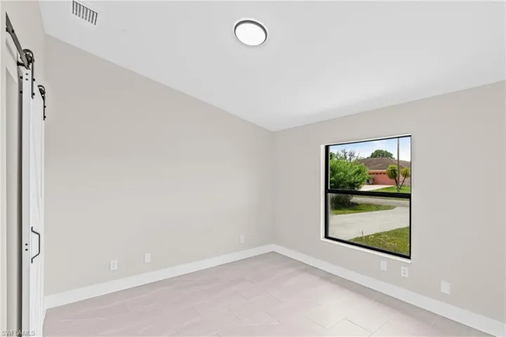 Spare room featuring a barn door and baseboards