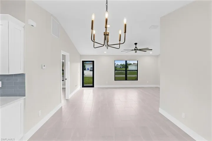 Unfurnished dining area featuring a chandelier, vaulted ceiling, and a ceiling fan