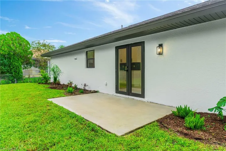 Back of house with stucco siding, a patio area, and french doors