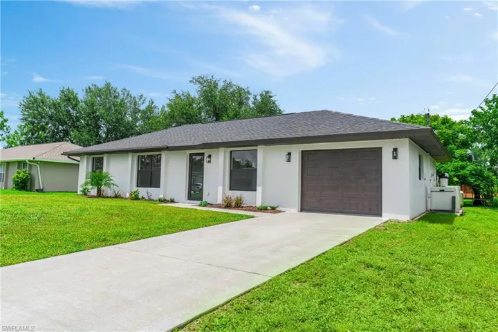 Single story home featuring stucco siding, a front lawn, concrete driveway, and a shingled roof