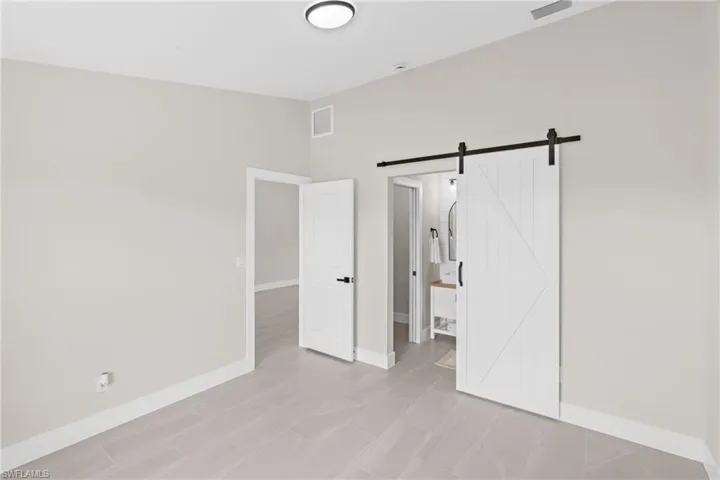 Unfurnished bedroom featuring a barn door and connected bathroom