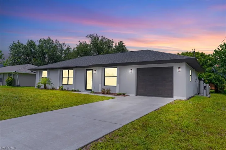 Ranch-style house featuring stucco siding, a shingled roof, a front yard, concrete driveway, and a garage