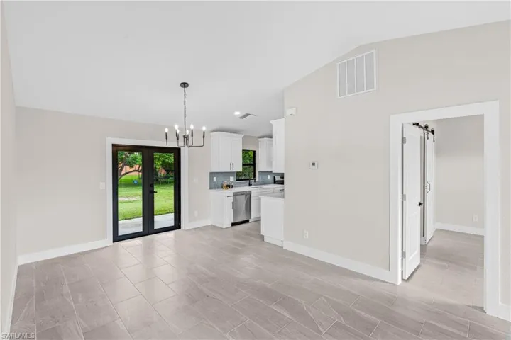 Unfurnished Dining room with a chandelier, vaulted ceiling, and french doors