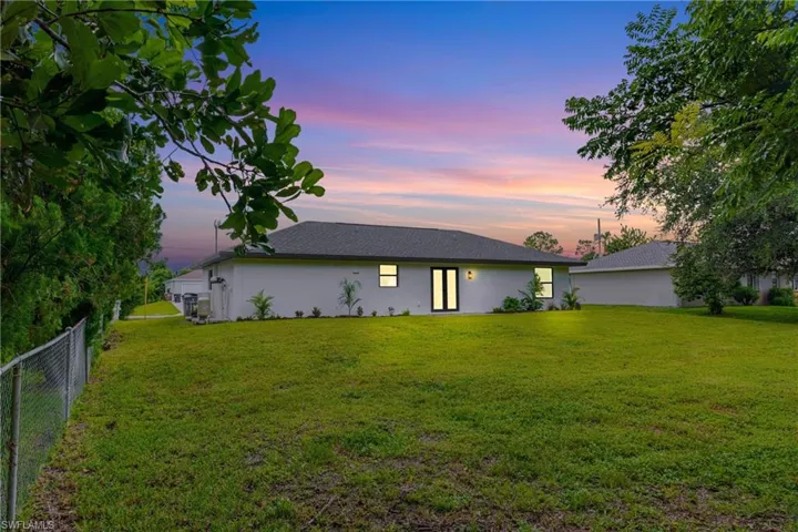 Rear view of property with stucco siding and roof with shingles