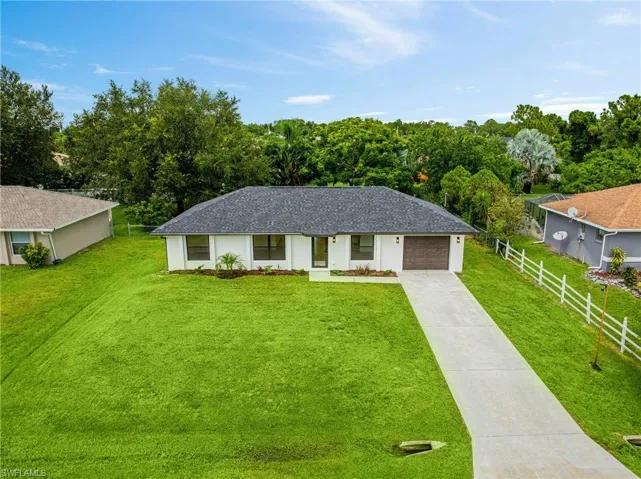 Ranch-style house featuring concrete driveway, roof with shingles, and a garage