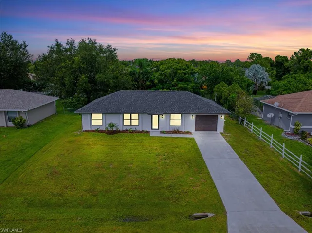 Single story home with driveway, a shingled roof, and stucco siding