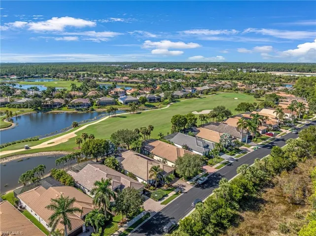 Aerial view of property and surrounding area featuring nearby suburban area, a local golf course, and a nearby body of water