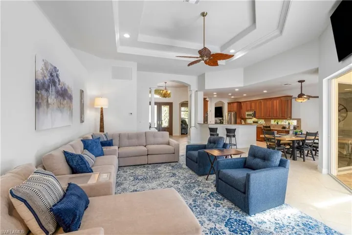 Living area featuring a ceiling fan, recessed lighting, arched walkways, a raised ceiling, and light tile patterned floors