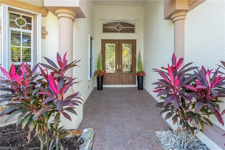 Doorway to property featuring french doors, stucco siding, and covered porch