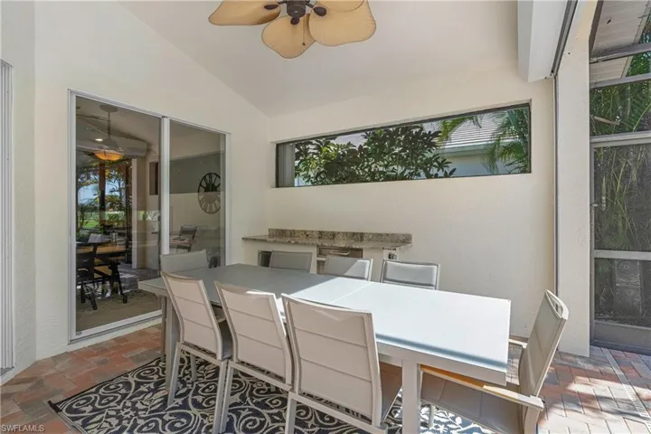 Sunroom with outdoor dining space, a patio area, a ceiling fan, vaulted ceiling, and an outdoor kitchen