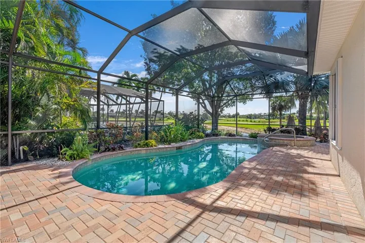 View of swimming pool with a sunroom, glass enclosure, a patio, and a pool with connected hot tub