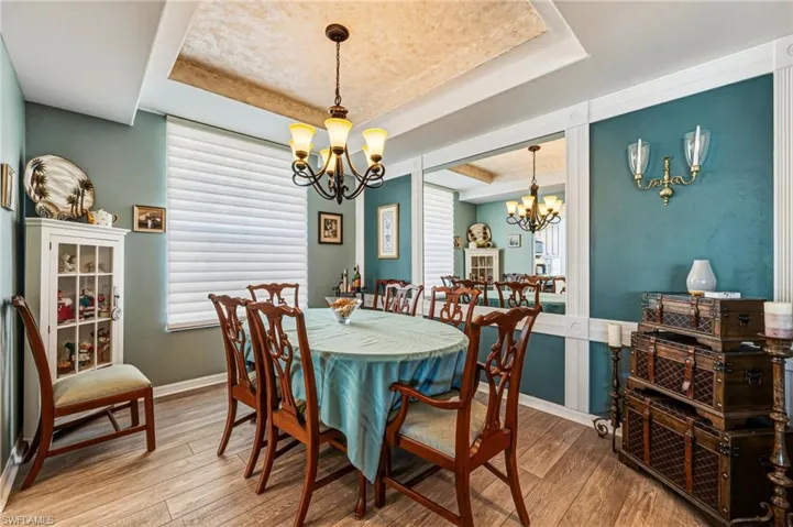 The formal dining area is ideally situated just off the kitchen, offering effortless flow for entertaining. Custom mirrors enhance the sense of space and light, while a tray ceiling adds an elegant architectural touch.
