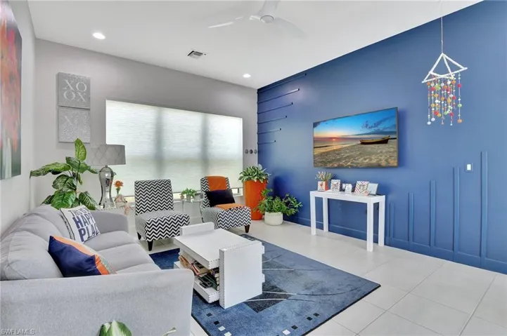 Living room with tile flooring and ceiling fan with notable chandelier