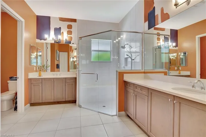 Bathroom featuring tile floors, a shower with frameless shower door, oversized vanity, and toilet
