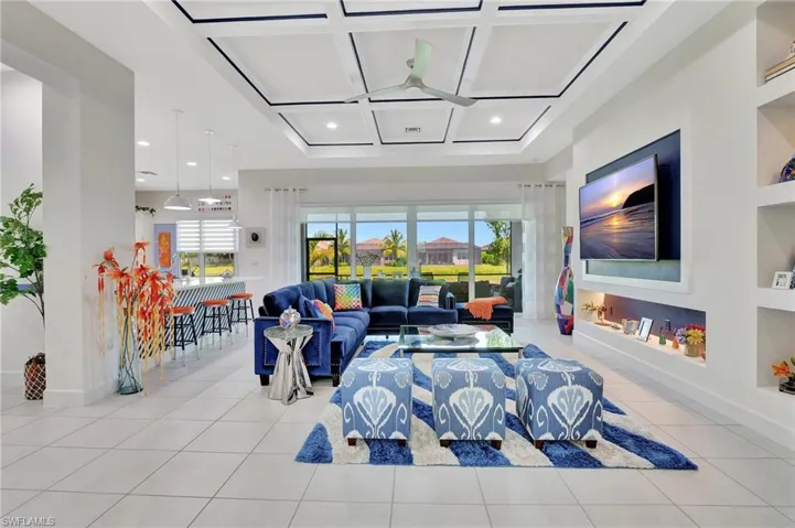 Tiled living room featuring coffered ceiling, built in shelves, and ceiling fan
