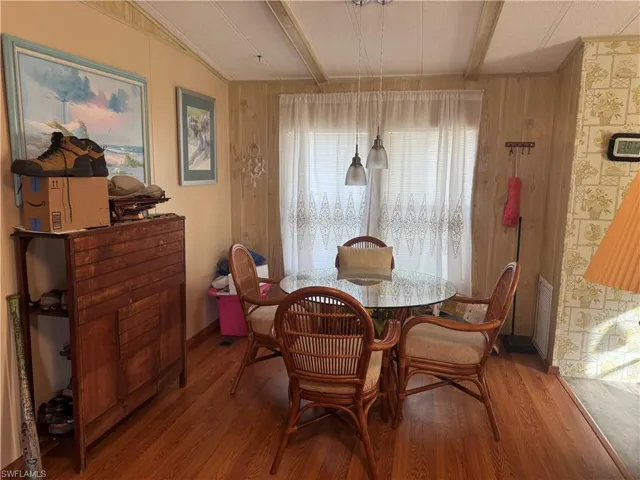 Dining space featuring beamed ceiling, wood finished floors, and wooden walls