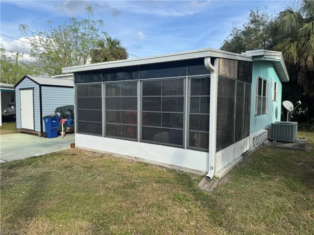 View of side of home featuring a lawn and a sunroom