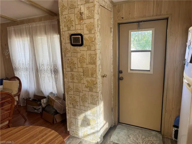 Doorway to outside with wood finished floors and beam ceiling