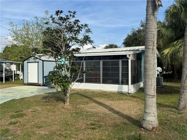 Back of house featuring a yard, a metal roof, a sunroom, and an outdoor structure