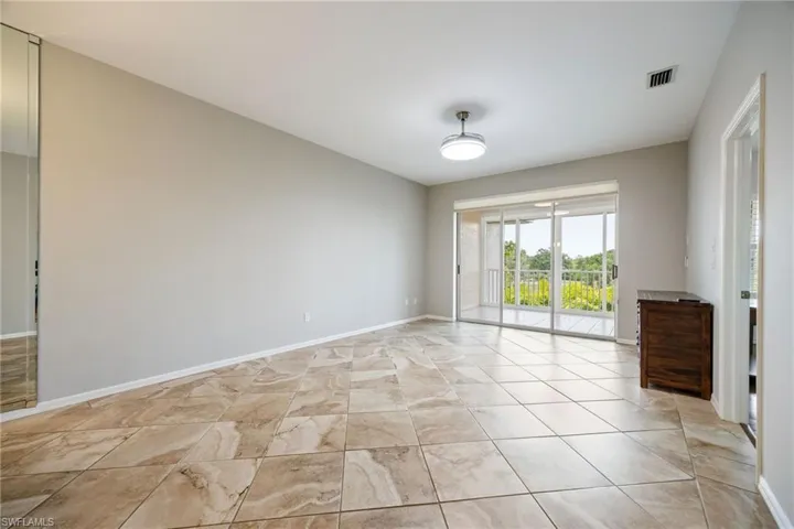 Living Room w/ open floor plan. Gorgeous views of golf course & mature florida landscaping. Door to right opens into primary bedroom. Recently painted w/ neutral palette.