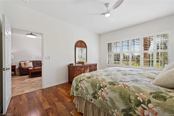 Primary Bedroom featuring Engineered Hardwood Flooring, Plantation blinds and a newly added Accordion style Hurricane Shutter. Off main living area and facing gulf course views.