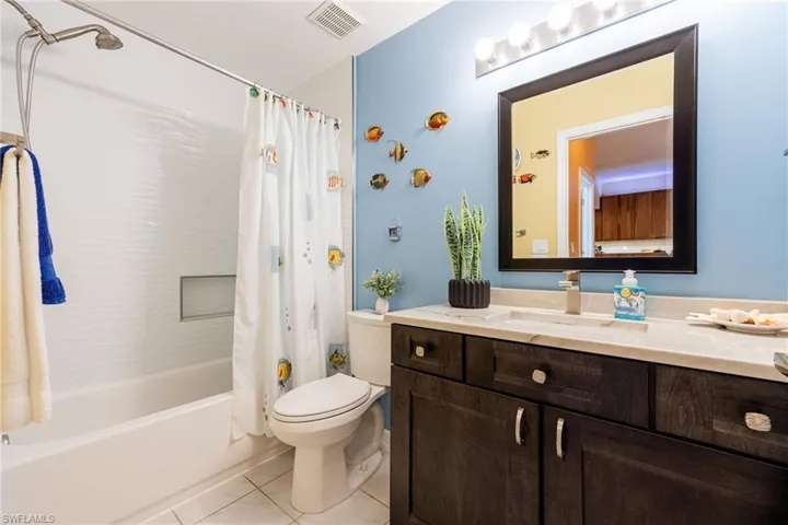 Fully renovated guest bathroom, soaking tub, custom tiling w/ and elevated look ~ tiles to the ceiling, toilet, vanity, granite countertop, mirror.