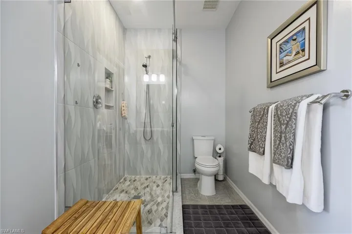 Fully renovated Primary Bathroom featuring custom tiling to the ceiling, glassed in shower, floor tiling, new upgraded toilet.